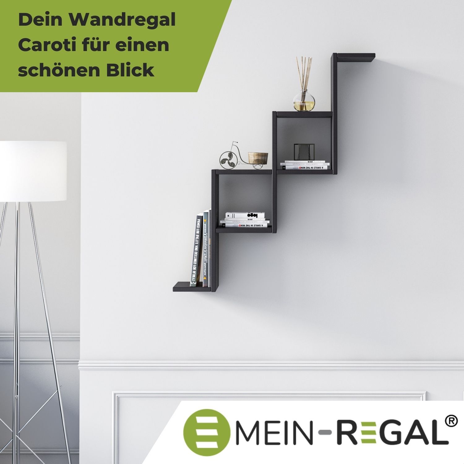 Wandregal Carotti Schwarz neben einer Stehlampe an grauer Wand hängend. Unten rechts das Logo Mein-Regal.