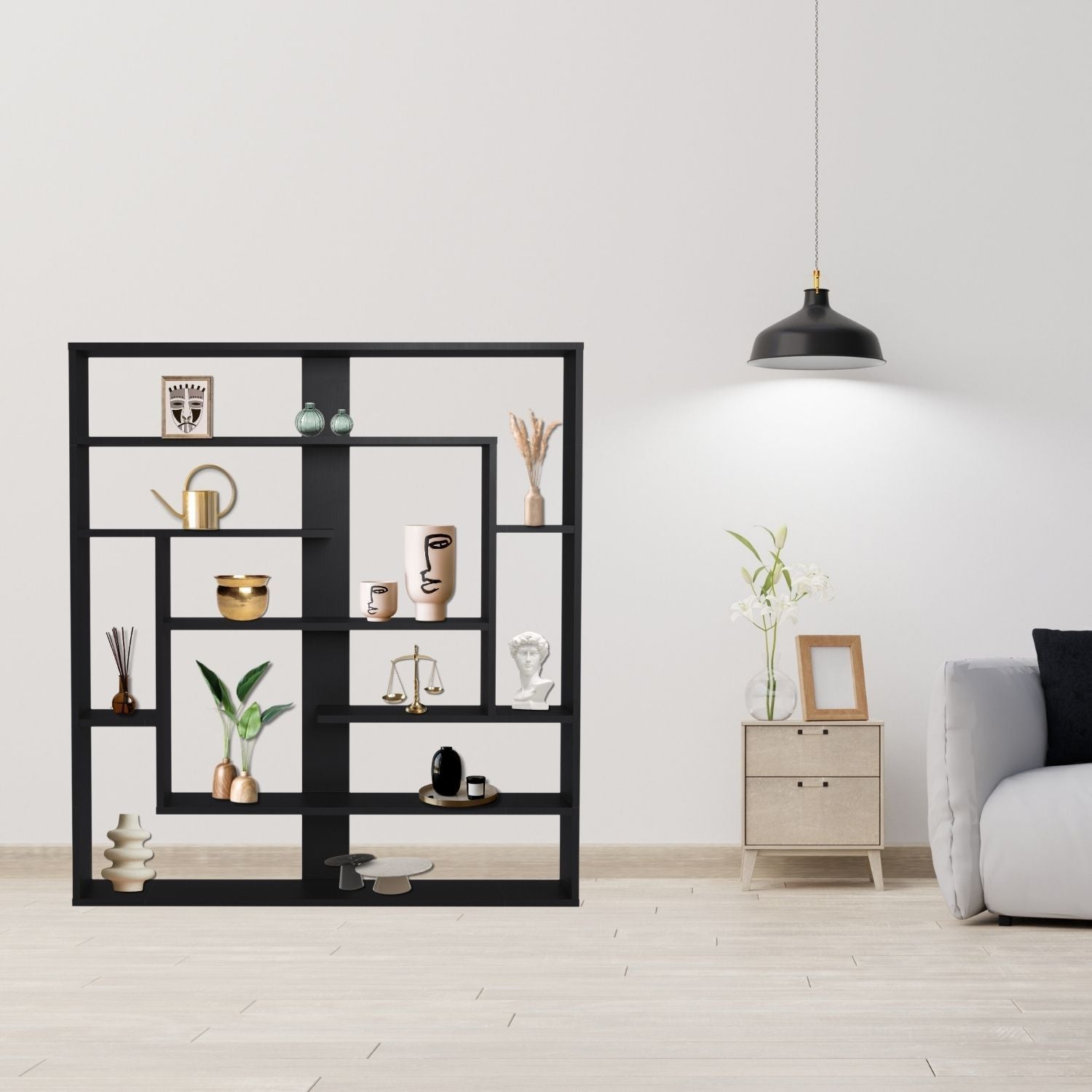 Wandregal Sebastian Schwarz im Zimmer an hellen Wand stehend neben einem kleinen Schränkchen und Sofa. Im Regal stehen Vasen, Pflanzen, Gießkanne, Figuren und Bilderrahmen.